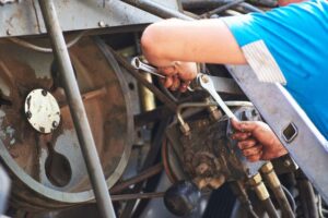 Combine machine service, mechanic repairing motor outdoors