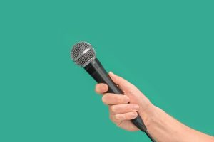 Interviewer or reporter with microphone in hand on green backgro