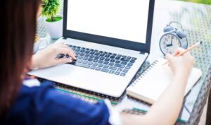 Close-up of business female working with laptop make a note of n