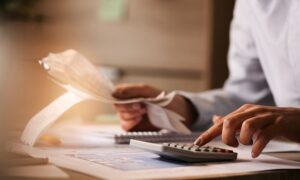 Close-up of business accountant using calculator while working i