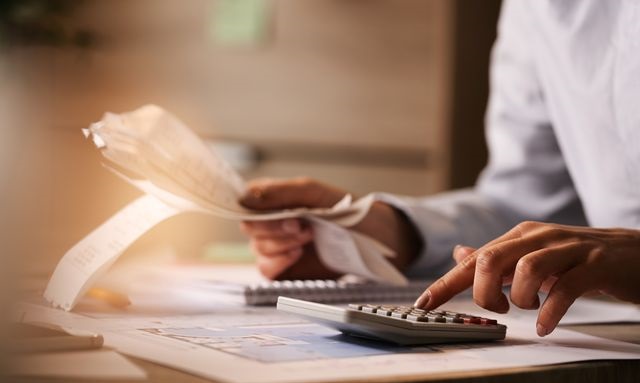 Close-up of business accountant using calculator while working i