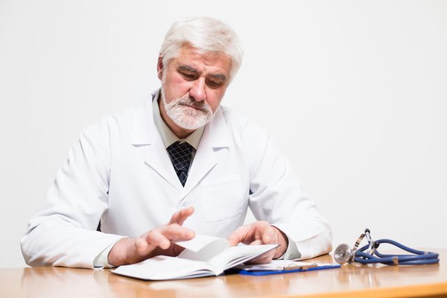 middle aged doctor with gray hair and beard reading his notes